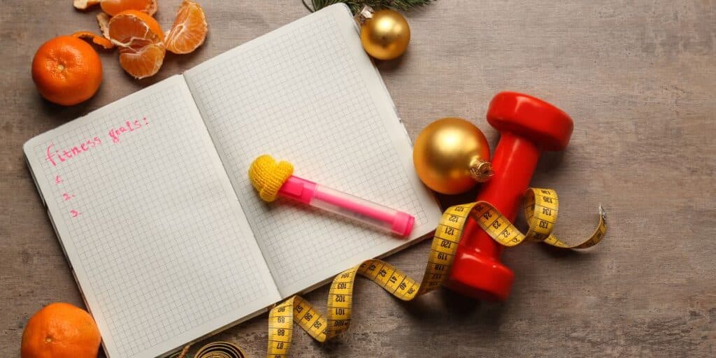 a notebook with a tape measure and a red dumbbell on it