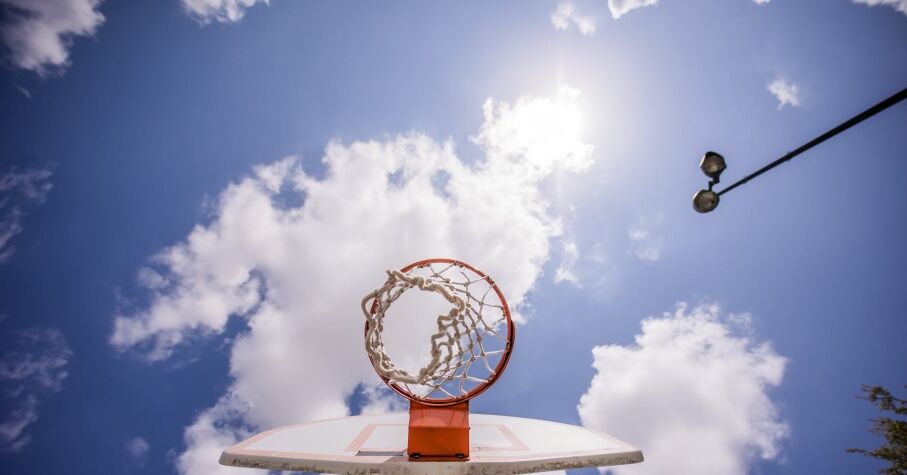 Basketball hoop hanging on backboard under sunshine